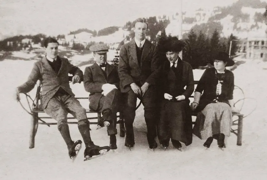 Friends in their best coats on a bench by an ice rink, early 1900s